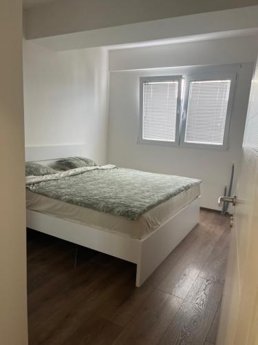 a bed in a white room with two windows at Lychnidos Residence 2 in Ohrid
