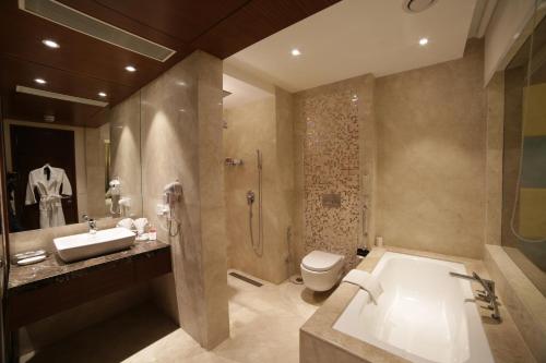 a bathroom with a tub and a toilet and a sink at The P L Palace Agra in Agra