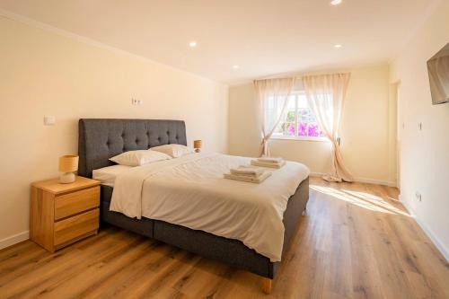 a bedroom with a large bed and a window at Vivenda Verivitor - Saltwater Pool, Garden, BBQ & Tennis Court in Sesimbra