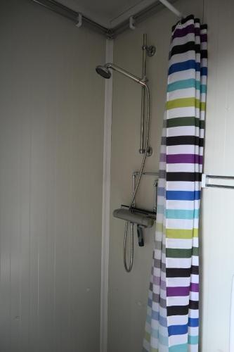 a shower curtain in a bathroom next to a refrigerator at Single room - small cabin - stuga - self check in - Gällivare Koskullskulle in Koskullskulle