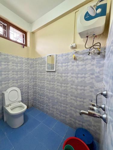 a bathroom with a toilet and a blue tile floor at Tenzin Homestay in Dirang Dzong