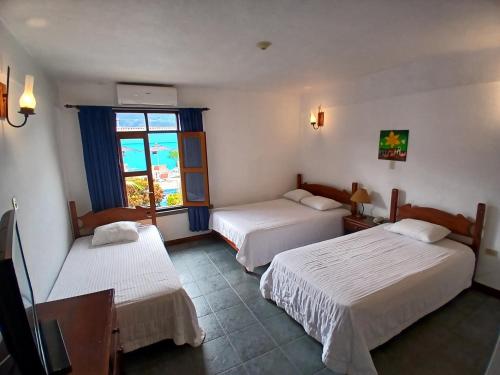 ein Hotelzimmer mit zwei Betten und einem Fenster in der Unterkunft El Serrano Hotel Merida in Mérida