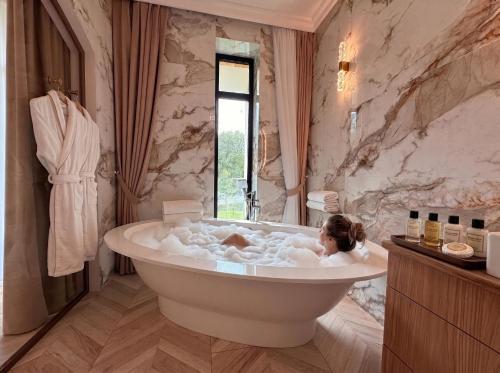 a woman laying in a bath tub in a bathroom at Lakes Places Villas in Kyiv