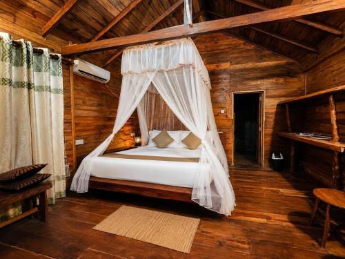 a bedroom with a bed with a mosquito net at wood cabin sigiriya in Sigiriya