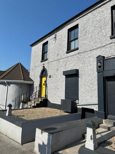 a white brick building with a yellow door at Edenderry Central Rooms in Edenderry