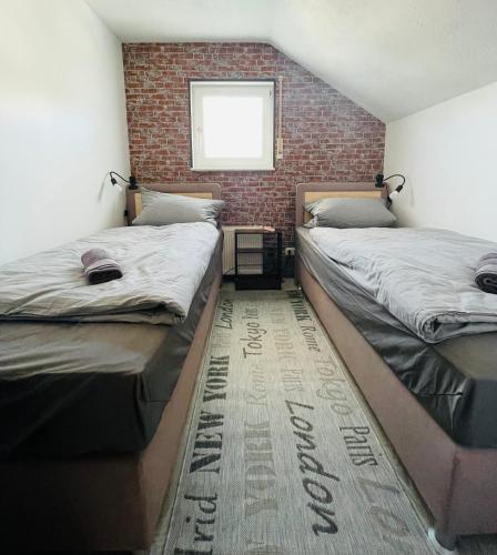 two beds in a room with a brick wall at LohainsLodge in Burbach
