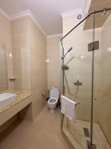 a bathroom with a toilet and a glass shower at Sapar de lux hotel in Qyzylorda