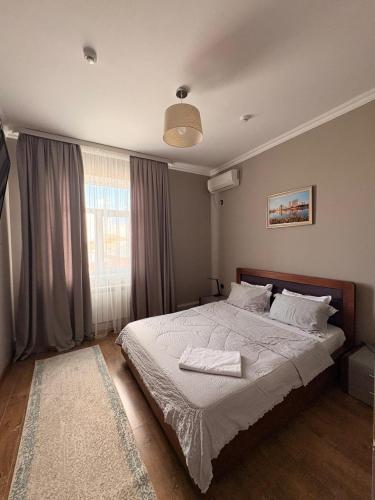 a bedroom with a bed with white sheets and a window at Sapar de lux hotel in Qyzylorda