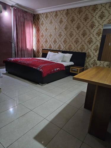 a bedroom with a bed with a red comforter at GRACECUT HOTEl in Enugu