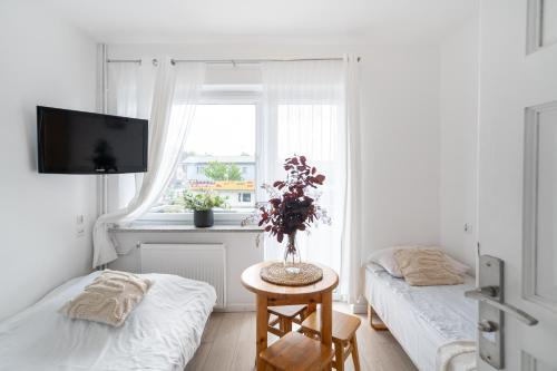 a bedroom with two beds and a table with a vase of flowers at Pokoje Złota Plaża in Międzywodzie
