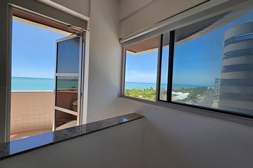 a room with a window with a view of the ocean at Lindo Duplex na orla de Pajuçara in Maceió