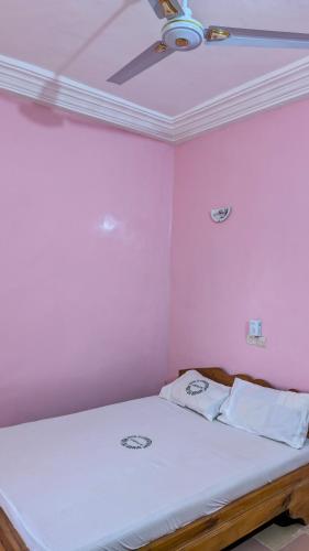 a bedroom with a bed with pink walls and a ceiling at Hôtel St Jo in Bohicon
