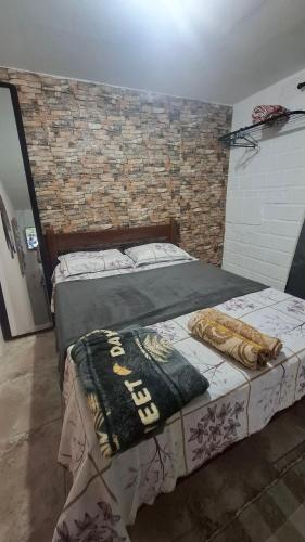 two beds in a room with a brick wall at Kitnetilha in Itamaracá