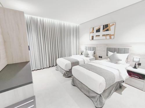 two beds in a hotel room with white walls at شقق الإيجار - العروبه in Riyadh