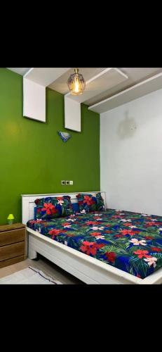 a bedroom with a bed with a green wall at Empereur City in Ouidah