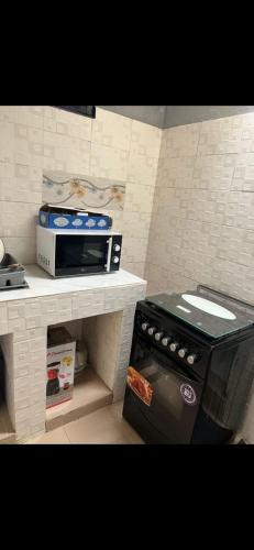 a kitchen with a stove and a microwave on a counter at Empereur City in Ouidah