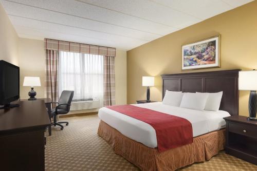 Habitación de hotel con cama, escritorio y TV. en Country Inn & Suites by Radisson, Frackville (Pottsville), PA, en Mount Pleasant