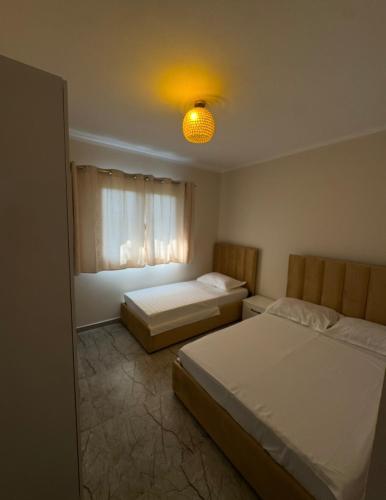 a bedroom with two beds and a light on the ceiling at Hotel Dalian in Baks-Rrjoll
