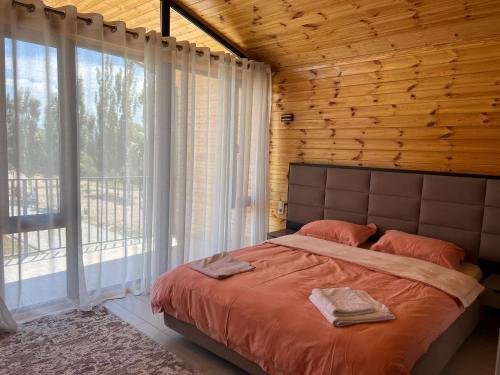 a bedroom with a bed and a large window at Atlantis Resort Коттеджи-таунхаузы in Chon-Sary-Oy