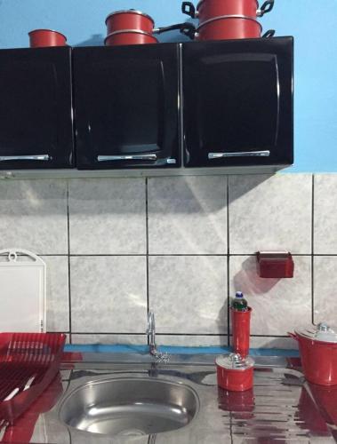 a kitchen counter with a sink and a microwave at Casinha de vó in Aracati