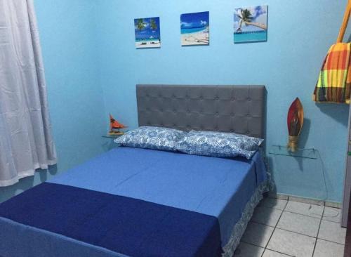 a blue bedroom with a bed with a blue wall at Casinha de vó in Aracati