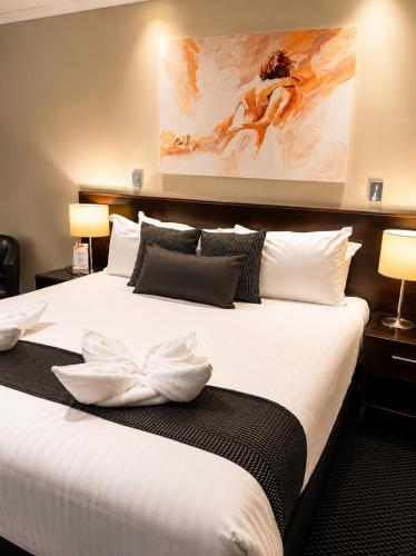a bedroom with a large bed with white sheets and pillows at ibis Styles Broken Hill in Broken Hill