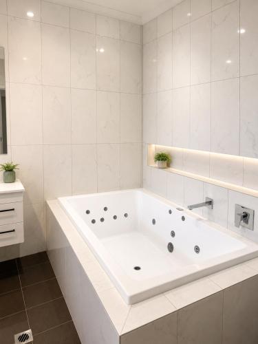 a white bathroom with a tub and a sink at ibis Styles Broken Hill in Broken Hill