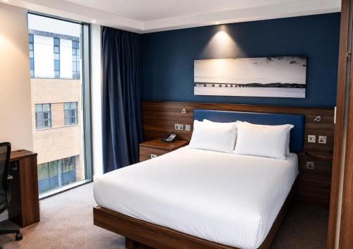 a bedroom with a large bed and a large window at Hampton by Hilton Dundee City Centre in Dundee