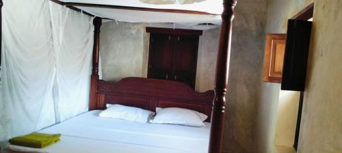 a bedroom with a canopy bed with white sheets at Lola House in Lamu