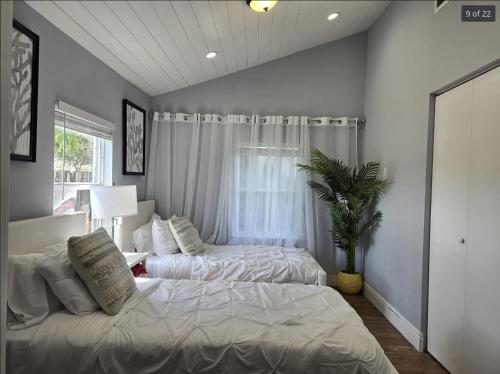 a bedroom with two beds and a potted plant at Endless Summer Cottage - Steps off Atlantic! in Delray Beach
