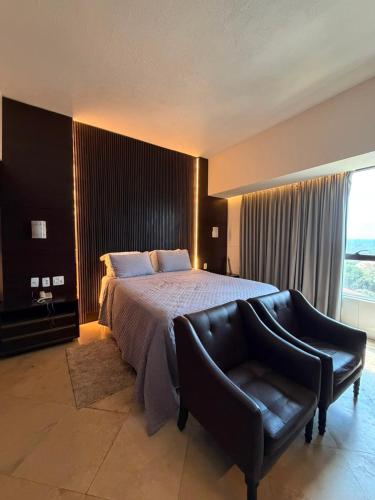 a bedroom with a bed and a leather chair at Tropical Executive Confort in Manaus
