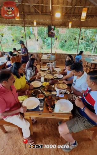 a group of people sitting at a table eating food at Skydeck - Boche 1000 Acre in Meppādi