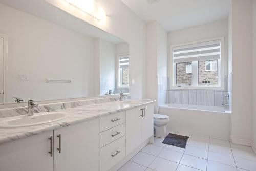 a white bathroom with two sinks and a toilet at Modern Luxury Townhouse in Cambridge