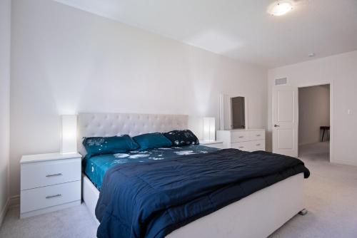 a white bedroom with a large bed with blue sheets at Modern Luxury Townhouse in Cambridge