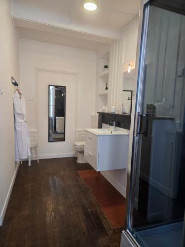 a white bathroom with a sink and a toilet at L'argonnière in Buzancy