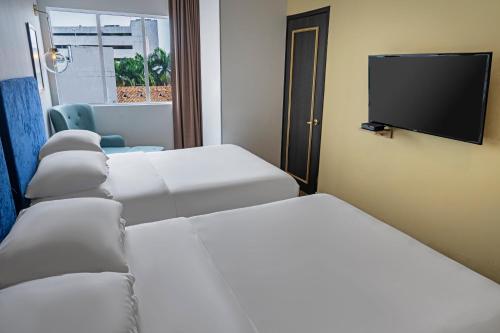 a room with three beds and a flat screen tv at Faranda Collection Cali, a member of Radisson Individuals in Cali