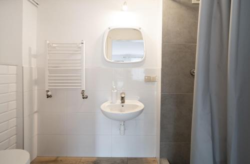 a white bathroom with a sink and a mirror at Pokoje Złota Plaża in Międzywodzie