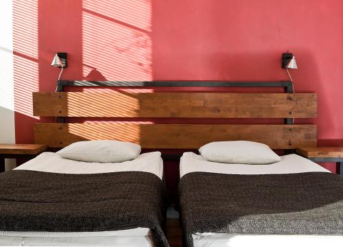 two beds in a room with a red wall at Hotelli Ville in Tampere