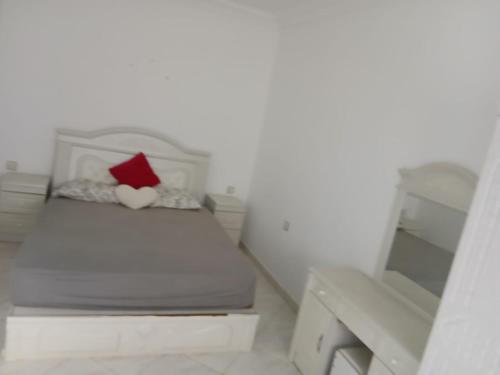 a white bedroom with a bed with a red pillow at Dardyafa in Larache