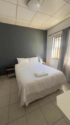 a bedroom with a large white bed with a window at River Gates Home in Rundu