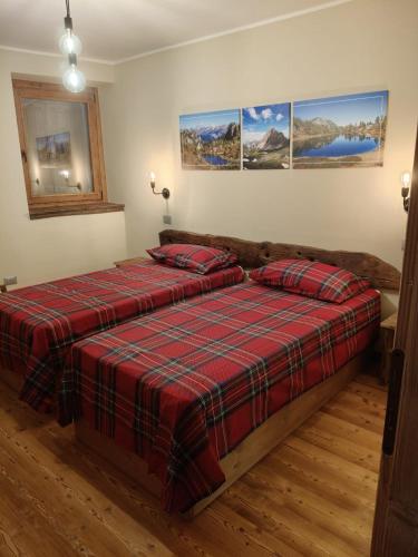 a bedroom with two beds with a red plaid blanket at La Sosto de Cesi - B&B in Grange Pieccia