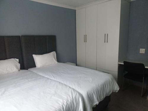a bedroom with two white beds and a chair at Lifeshed Guest Home in Johannesburg