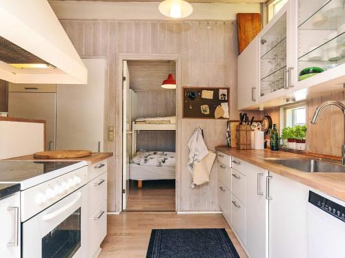 a kitchen with white cabinets and a bunk bed at 5 star holiday home in Væggerløse in Bøtø By