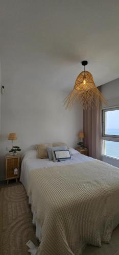 a bedroom with a large bed and a chandelier at SeaFront Horizon in Sitio de Calahonda