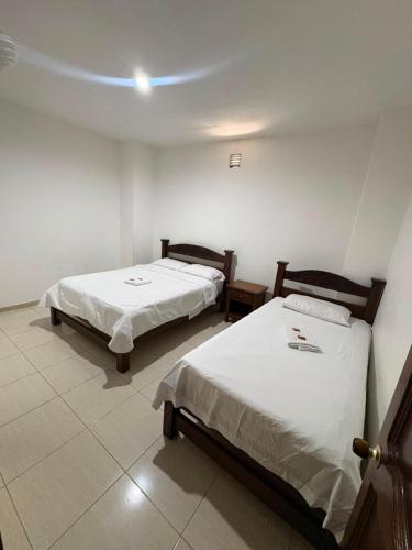 two beds in a room with white walls at ConfortTrust Hotel in Ocaña