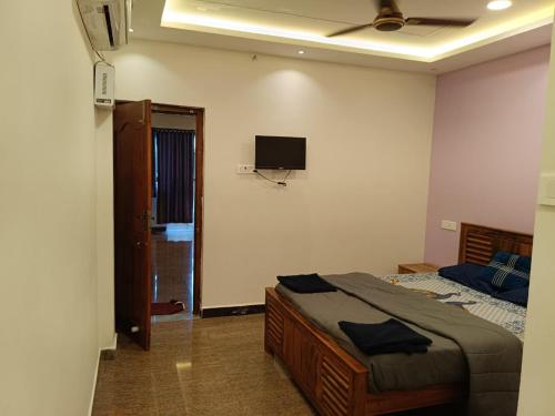 a bedroom with a bed and a tv on the wall at white sand villa in Tirupporūr