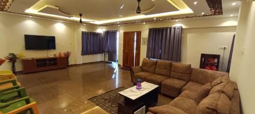a living room with a couch and a tv at white sand villa in Tirupporūr