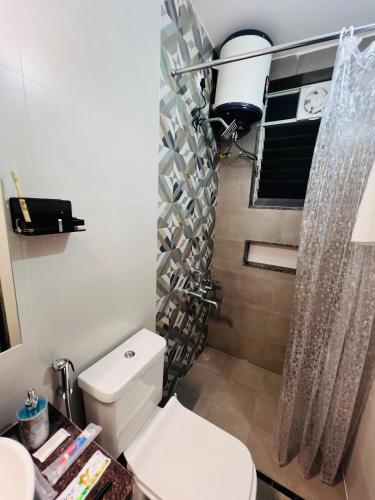 a bathroom with a toilet and a shower curtain at Verdant vista Goa in Cunchelim