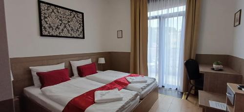 a bedroom with a bed with red pillows and a window at Víghajós Panzió in Budapest