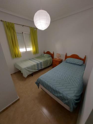 a bedroom with two beds and a lamp and a window at Le paradis de Lynn in Formentera de Segura
